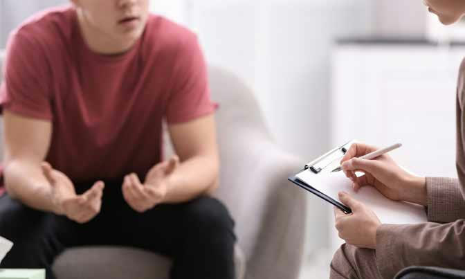 A young man talking with a counselor holding a clipboard