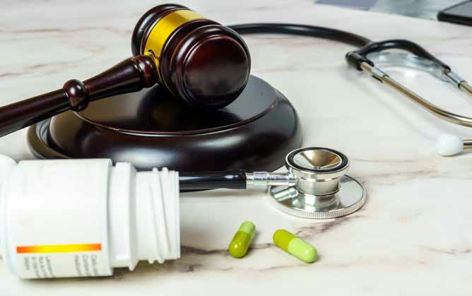 A gavel beside a stethoscope and a spilled pill bottle