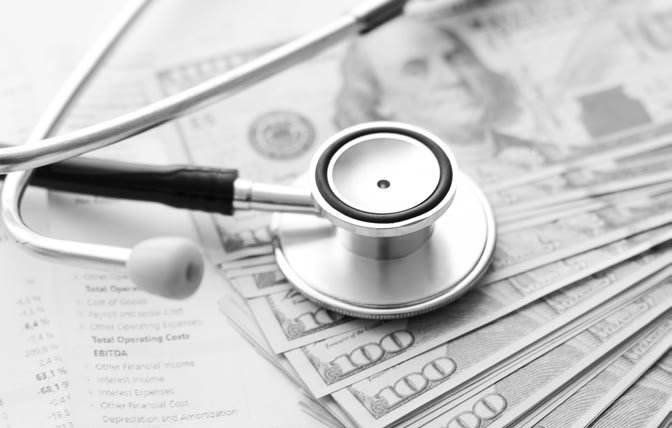 A stethoscope on a pile of hundred-dollar bills