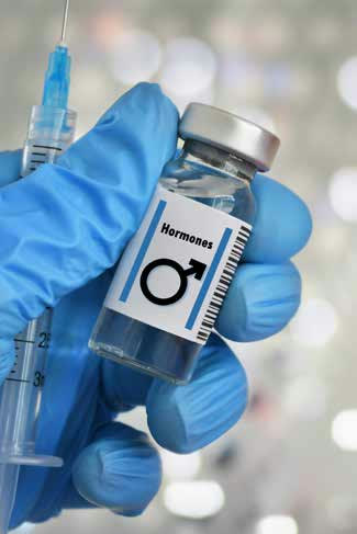 A gloved hand holding a vial labeled Hormones next to a syringe