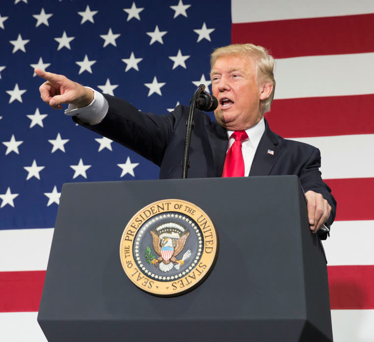President Donald Trump speaking at a podium in front of an American flag